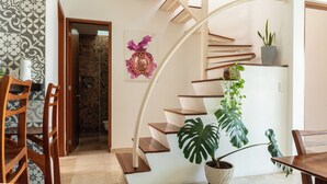 Ein modernes Interieur mit einer geschwungenen Treppe, einem Essbereich mit Holzbeschichtungen und einer Topfpflanze.