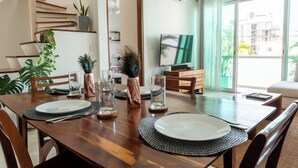 Ein Essbereich mit einem Holztisch, gedeckt für zwei Personen, einem Fernseher und einer Treppe, die zu einer oberen Etage führt.