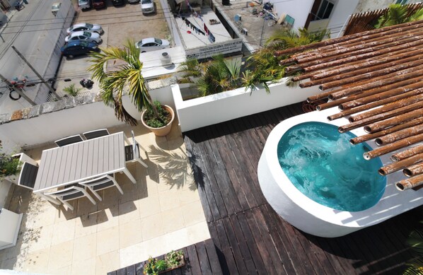 Ein Pool auf dem Dach mit Bambus-Geländern, eine Sitzgelegenheit mit Tisch und Stühlen sowie ein Blumentopf.