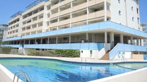 A multi-story hotel with a swimming pool in front.