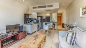 Una sala de estar moderna con un televisor de pantalla plana, una mesa de centro de madera y un sofá con un cojín a rayas.