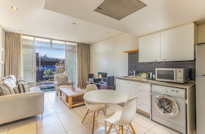 Une cuisine moderne équipée d’un lave-linge, un coin repas avec une table et des chaises, et un canapé.