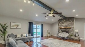 A modern living room with a stone fireplace, grey sofa, and a ceiling fan. - Cozy house in a heart of Mandarin (Jacksonville)