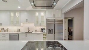 A modern kitchen with white cabinets, a built-in oven, and a stainless steel refrigerator. - Cozy house in a heart of Mandarin (Jacksonville)
