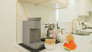 A kitchen with a coffee maker, a mug, and a watermelon-shaped coaster.