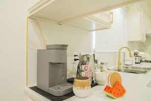 A kitchen with a coffee maker, a mug, and a watermelon-shaped coaster. - A cozy bunglow in Naigara Falls! (Niagara Falls)