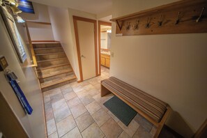 Un pasillo con un banco de madera, una puerta que da a un baño y un perchero.