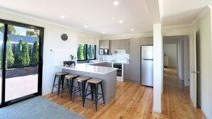 Une cuisine moderne dotée d’un îlot central, de tabourets de bar et offrant une vue sur l’extérieur.