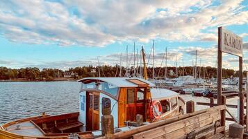Un port de plaisance avec des bateaux amarrés, un bateau en bois doté d’une cabine, et une enseigne sur laquelle on peut lire « KARÖN ».