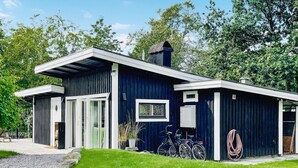 Uma casa moderna com fachada azul escura, uma grande porta de vidro e uma pequena janela com vidro decorativo.