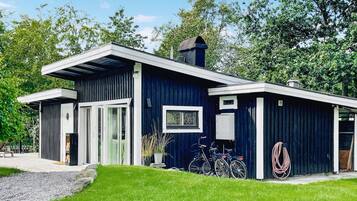 Ett modernt hus med en mörkblå fasad, en stor glasdörr och ett litet fönster med dekorativt glas.