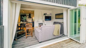 Un salon confortable avec un canapé, une table à manger et des chaises, un téléviseur fixé au mur et une cheminée.