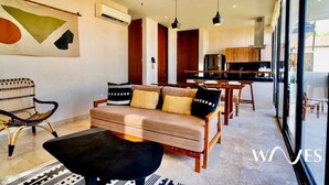 Uma sala de estar moderna com um sofá, uma cadeira preta e um espaço de jantar com mesa e cadeiras.
