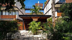 A modern building with a wooden facade, a sign reading "tuluma", and lush tropical plants. - 2 Br. Spacious Great Located Top Amenities (Tulum)