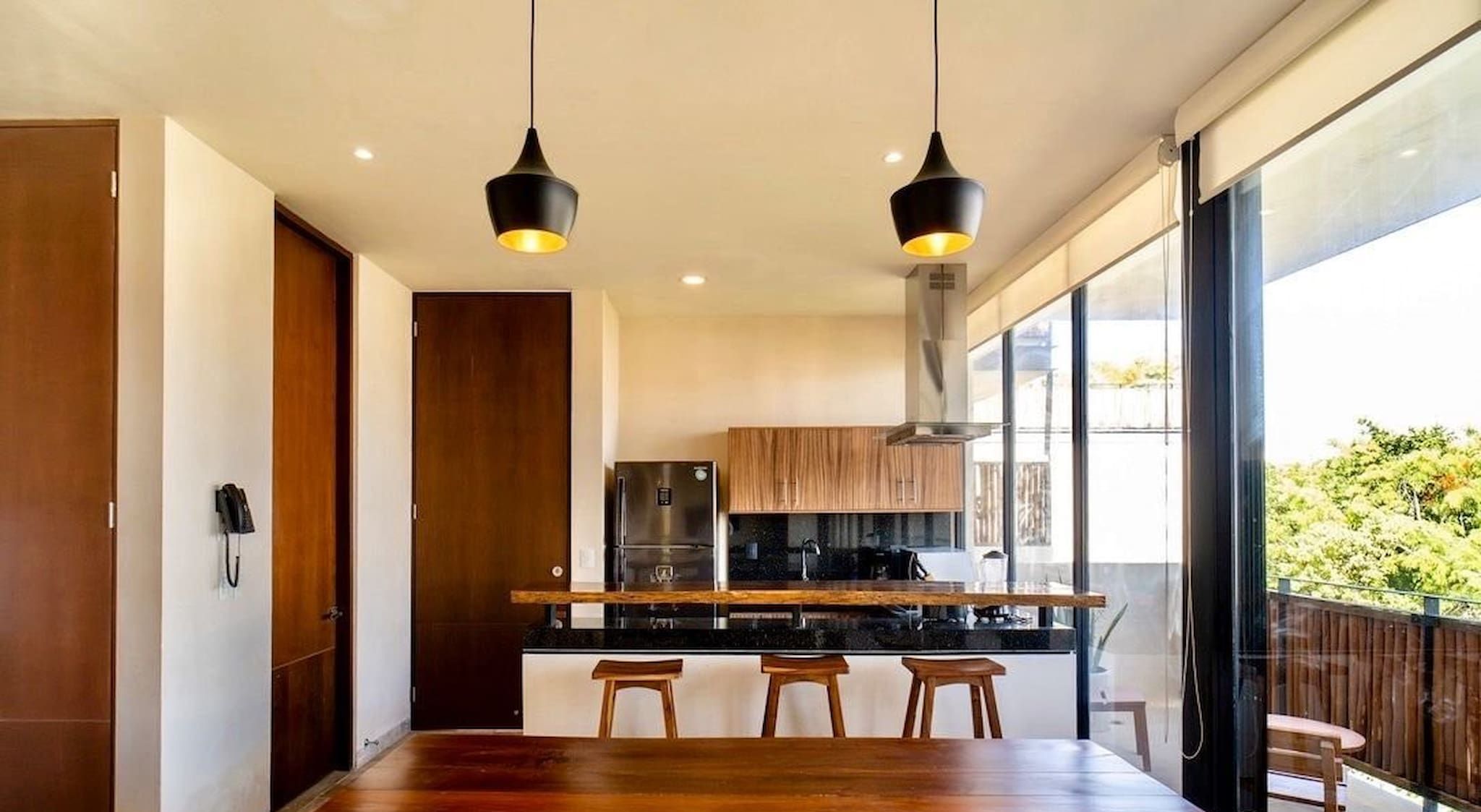 Een moderne keuken met een centraal eiland, houten kastjes en hangende verlichting.
