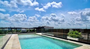 A rooftop swimming pool with clear blue water, surrounded by glass railings and potted plants. - 2 Br. Spacious Great Located Top Amenities (Tulum)