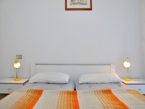 Un lit double avec deux oreillers, une table de chevet avec une lampe et un tableau encadré au mur.