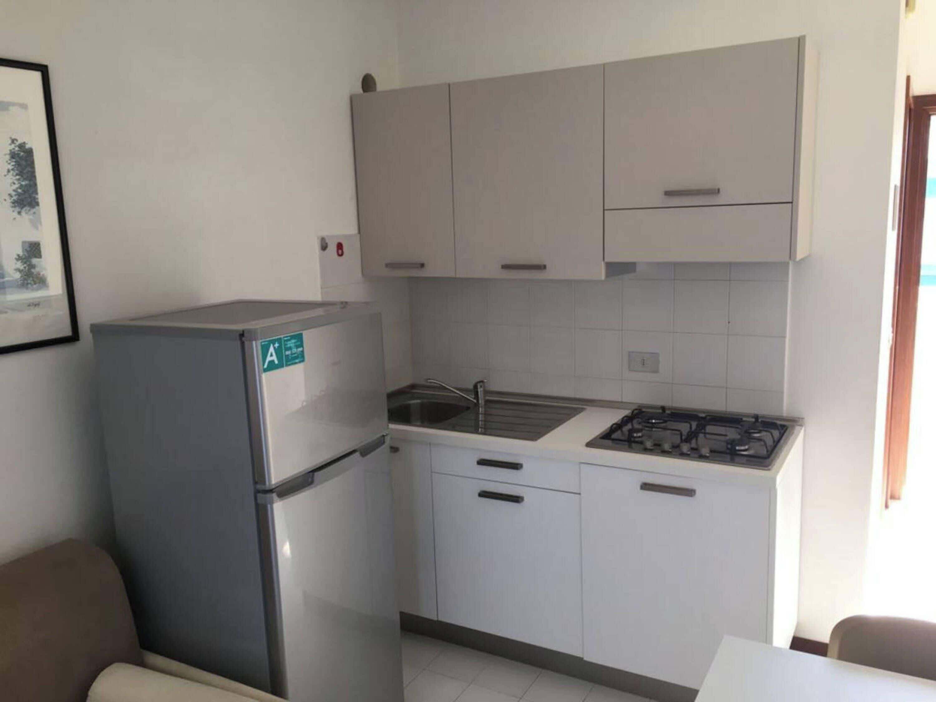 Una cuina compacta amb nevera, rentapelats i fogó.