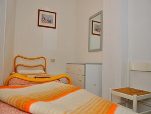 Une chambre à coucher comprenant un lit, une commode, une chaise et deux tableaux encadrés accrochés au mur.