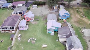 An aerial view of a residential area with houses, a grassy yard, and a dock. - Hummingbird Cottage: Cozy Rustic Lakefront Escape at The Pier, Perfect for 7! (Union City)