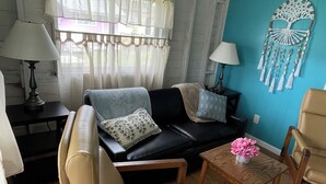 A cozy living room with a sofa, chairs, a coffee table, and a decorative wall piece. - Hummingbird Cottage: Cozy Rustic Lakefront Escape at The Pier, Perfect for 7! (Union City)