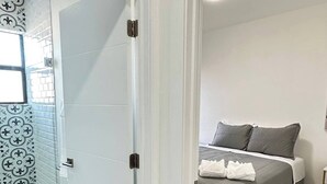 Een hotelkamer met een bed, een nachtkastje en een badkamer met douche.