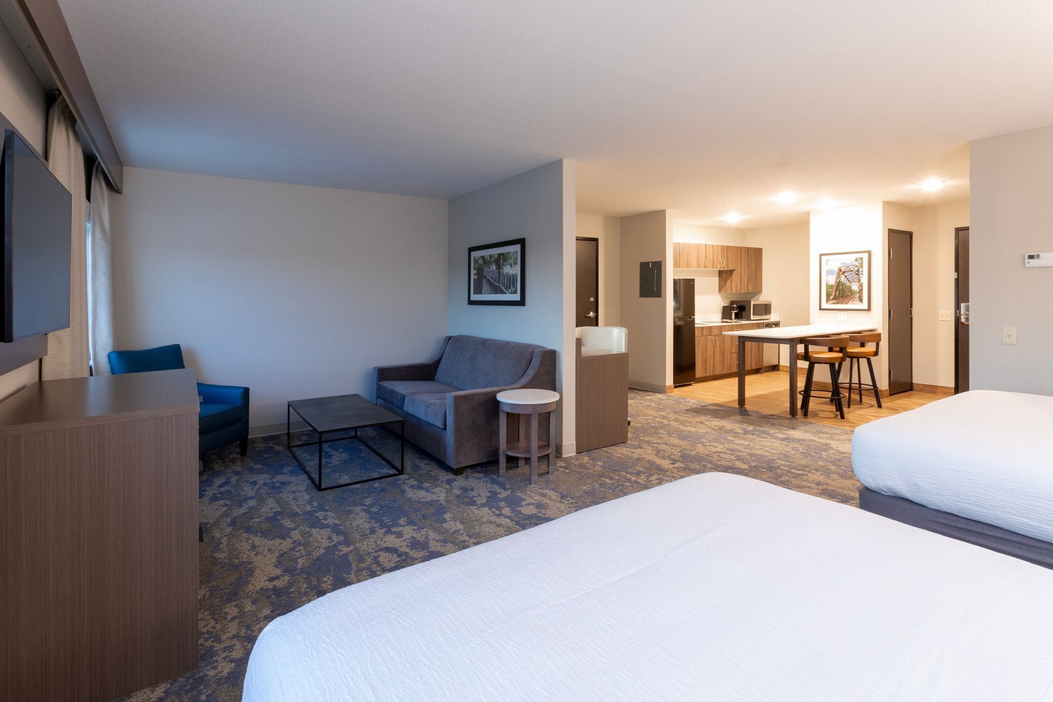 Habitación de hotel con dos camas, un escritorio, una silla, un sofá y una mesita.