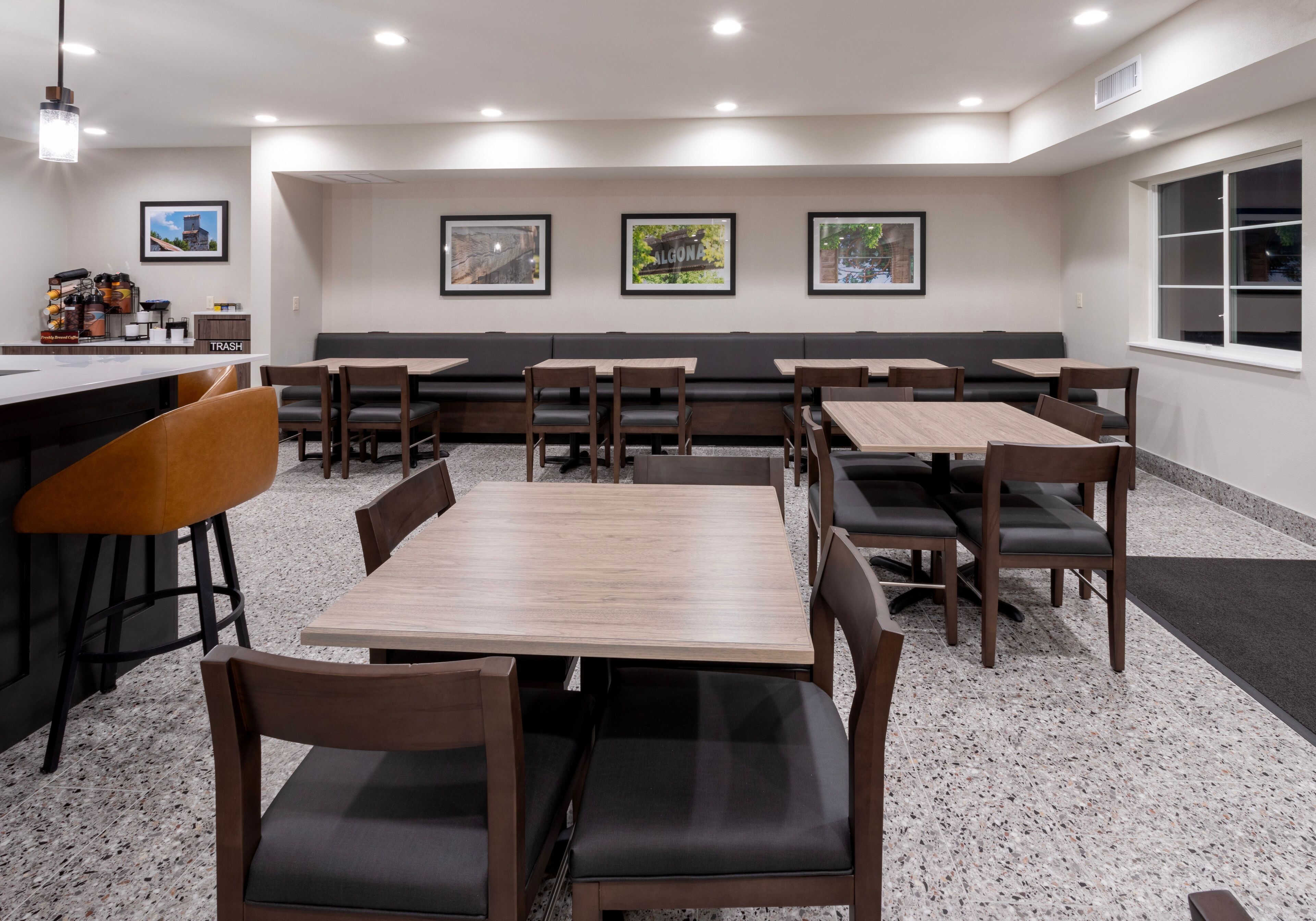 A restaurant with multiple tables and booths, a bar area, and framed pictures on the wall.