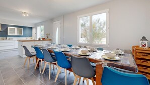 Eine moderne Küche mit Essbereich, großen Fenstern und Blick ins Freie.