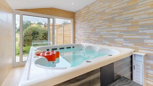 Ein modernes Badezimmer mit einer Glaskonstruktion für eine Hot Tub, einer Holzbalkendecke und einer Wand mit Muster.