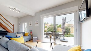 Ein modernes Wohnzimmer mit einem grauen Sofa, gelben Kissen, einem kleinen runden Tisch und einer Treppe.