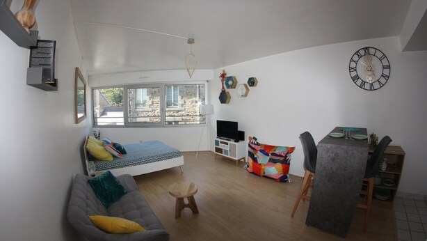 A modern living room with a bed, sofa, dining table, and a TV. - Studio de 33 m² en Centre-ville (Saint-Brieuc)