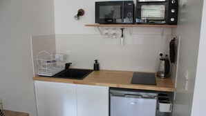 A compact kitchen with a dishwasher, a microwave, and a toaster oven. - Studio de 33 m² en Centre-ville (Saint-Brieuc)