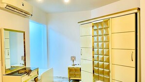 Un dormitorio con cama, tocador con espejo, cómoda y armario.