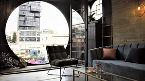 Un salon moderne avec une fenêtre ronde, un canapé, un fauteuil et une table basse.