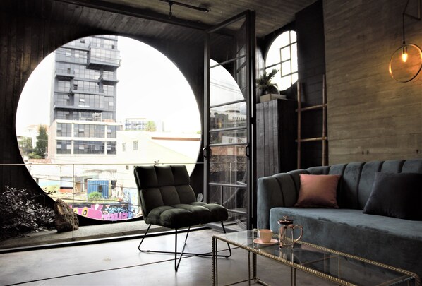 Ein modernes Wohnzimmer mit einem Rundfenster, einer Couch, einem Sessel und einem Couchtisch.