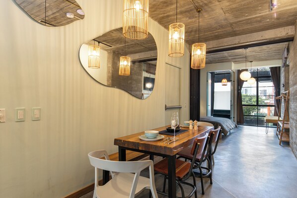 A dining area with a wooden table, chairs, and hanging lights.