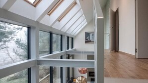 A spacious interior with high ceilings, large windows, and a view of trees outside.