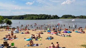 A crowded beach with people sunbathing and swimming.