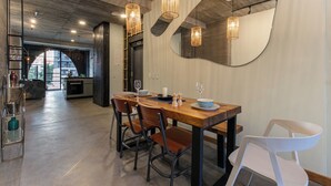 Un comedor moderno con una mesa de madera, cuatro sillas e iluminación colgante.