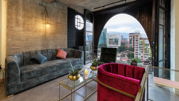 Una sala de estar moderna con un sofá gris, un sillón rojo y una mesa de centro de vidrio.