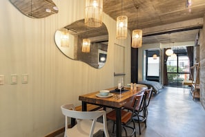 Uma sala de jantar com mesa de madeira, cadeiras e luminárias pendentes.