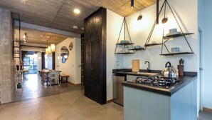 Une cuisine moderne dotée d’un îlot central, de luminaires suspendus et d’étagères intégrées.