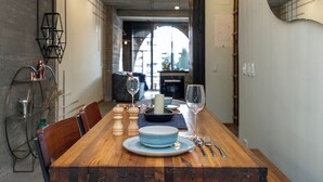 Une table à manger dressée avec des assiettes bleues, un bol et des couverts, et une chaise en bois placée d’un côté.