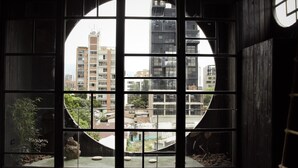 Une pièce dotée d’une grande fenêtre circulaire qui offre une vue sur les bâtiments de la ville.