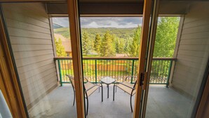A balcony with a table and chairs, offering a view of a forested area and distant hills. - Gateway Lodge 5015 (Keystone)