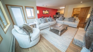A spacious living room with a grey sofa set, a coffee table, and a red accent wall. - Gateway Lodge 5015 (Keystone)