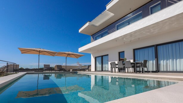 A modern two-story building with a swimming pool, outdoor seating, and large windows. - Stunning home in Lun with sauna (Lun)