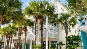 Un hotel de varios pisos, con terraza al aire libre y palmeras.