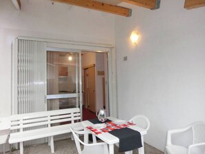 A small dining area with a table, two chairs, a bench, and a wall-mounted light fixture. - Cozy Villa Steps From the Beach (San Michele al Tagliamento)